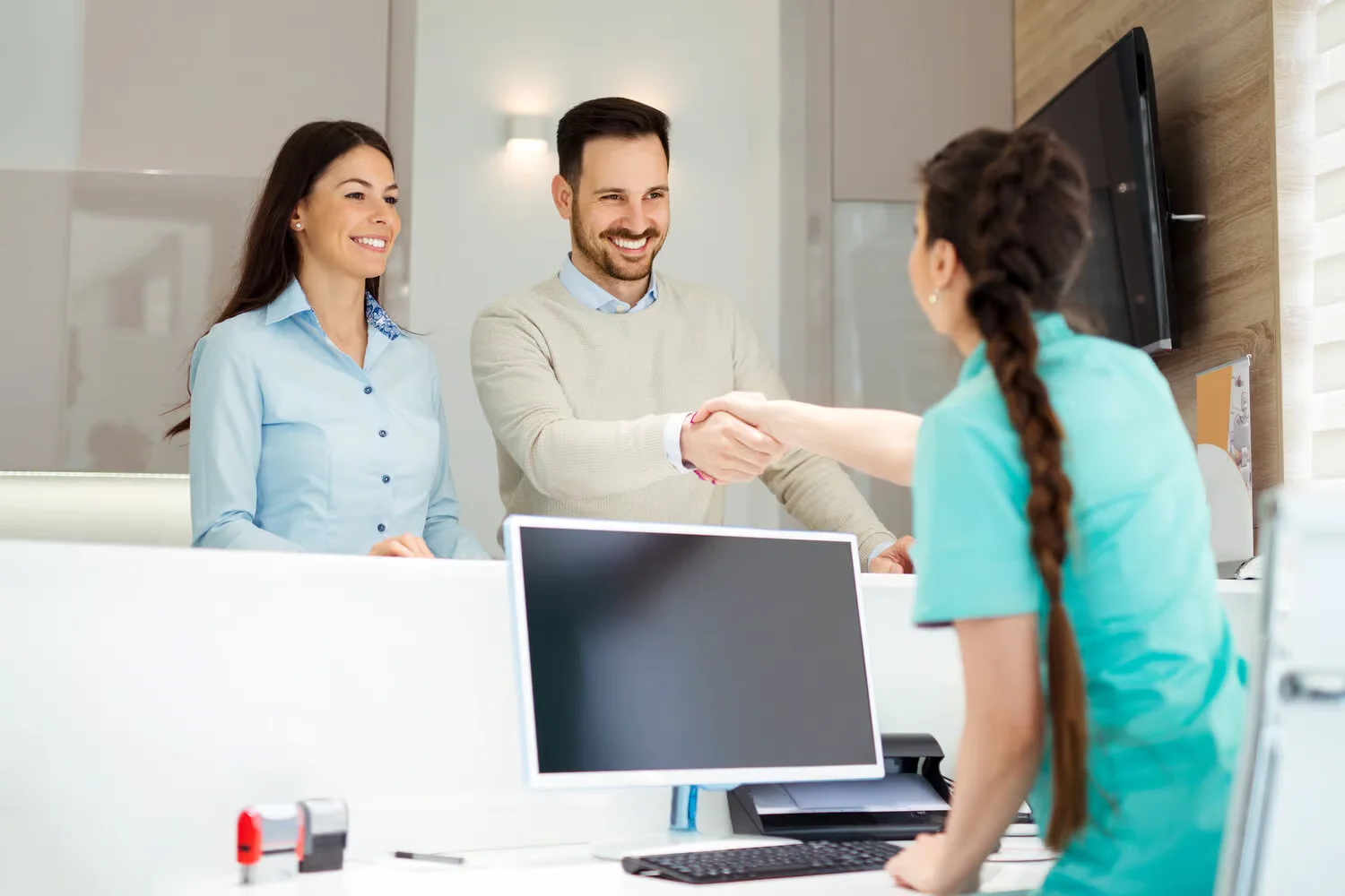 Friendly front desk team welcoming a patient at check-in