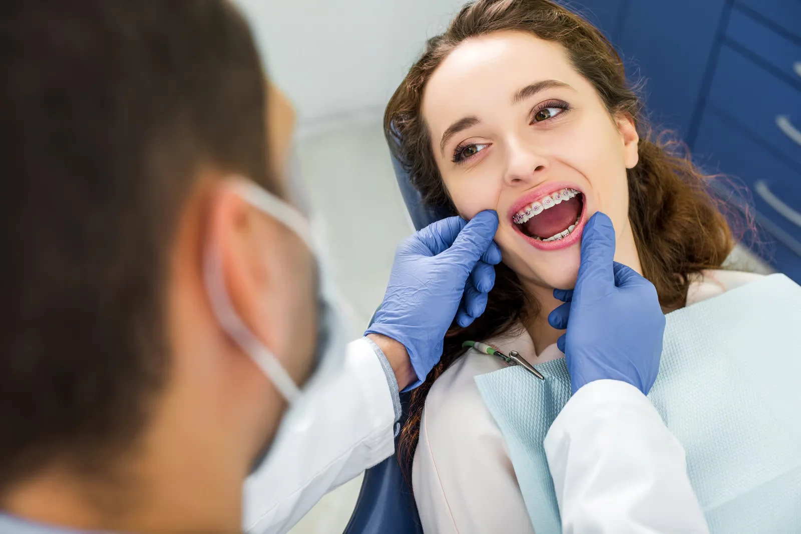 Orthodontist checking a smiling patient's braces